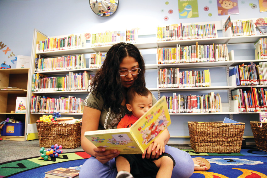 Leslie Belmontes, 19, reads with her 2-year-old son, Aaron, at the Bear Valley Branch Library in Denver. Belmontes dropped out of high school after becoming a mom.