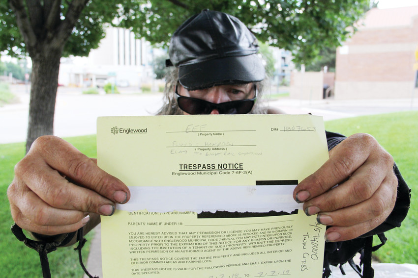 Randall Thompson, a man who has been homeless for 5 1/2 years in the Denver metro area, holds up a trespass notice he was issued on July 7 near the Englewood Civic Center, 1000 Englewood Parkway. He stood three blocks to the east, now banned from that area. Thompson, in his late 50s, frequently comes to the CityCenter Englewood shopping center along West Hampden Avenue, a few blocks west of South Broadway.