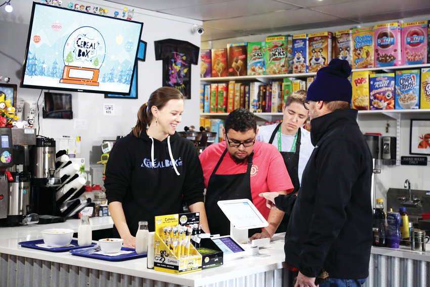 Lori Hofer, co-owner of The Cereal Box, teaches Jeffco Transitions students Jareth Guzman-Cortes and Jace Tausan how to ring up an order.
