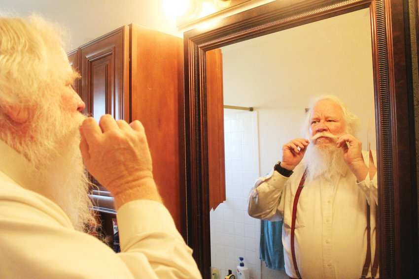 Bryan Austin, 60, primps his mustache before a Nov. 9 Christmas party hosted by a local Mothers of Preschoolers group. It takes about 30 minutes for Austin to sculpt his beard and mustache to look like Santa’s.
