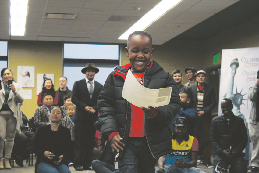 After receiving his citizenship certificate, Griffin Walugembe smiles down at the document.