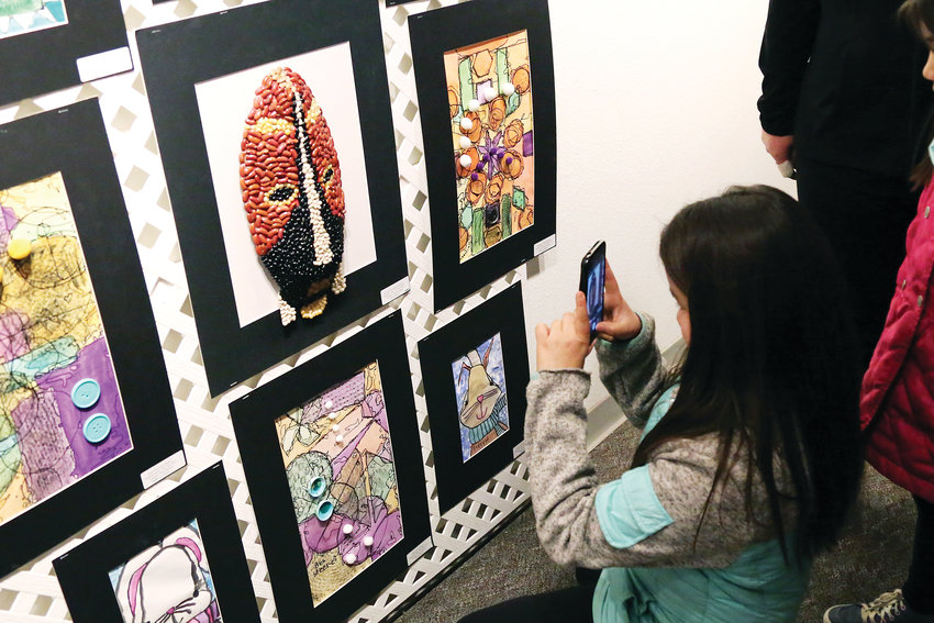 Korryn Domgaard, fourth-grader at Mitchell Elementary, takes a picture of her mixed media art on display at the Elementary Jeffco Schools Foundation Art Exhibit.