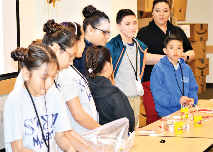 A group of STEM Launch students show some of their experiments to Amazon employees during a tour of the facility April 10. Later, the company donated $25,000 to the school to help purchase equipment.