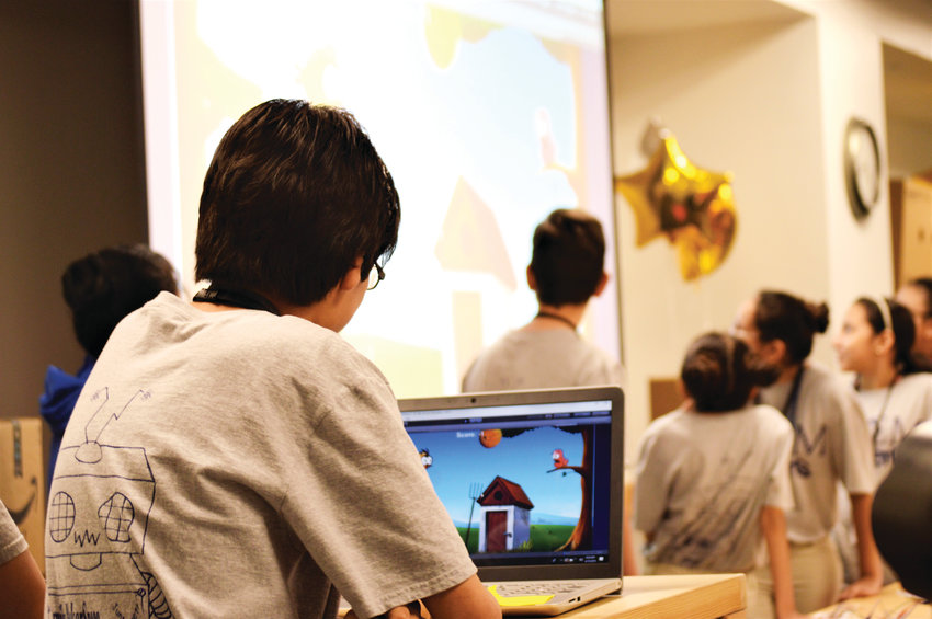Seventh-grader Angel Martinez demonstrates a video game he built using the C# programming language big screen inside Amazon's Thornton warehouse April 10. Martinez said he does not have a computer at home but built the game during his spare time in the STEM Launch school's maker lab.