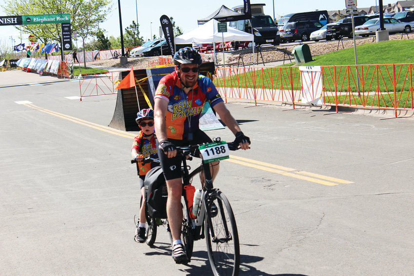 A man rides a tandem bike with his son as they both finish their ride June 2 during the Elephant Rock cycling event.