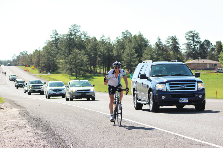 A cyclist smiles as traffic passes him on Highway 83 near Franktown June 2 during the annual Elephant Rock Ride.