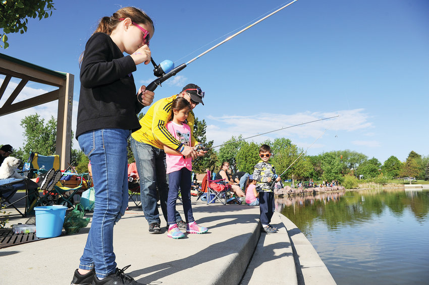 Antonio Soto, of Westminster, center, assists daughter Sadia, 7, with her fishing rod, as siblings Theresa, left and Victor, look on, during Northglenn's Annual Fishing Derby June 1, at E. B. Rains, Jr. Park.