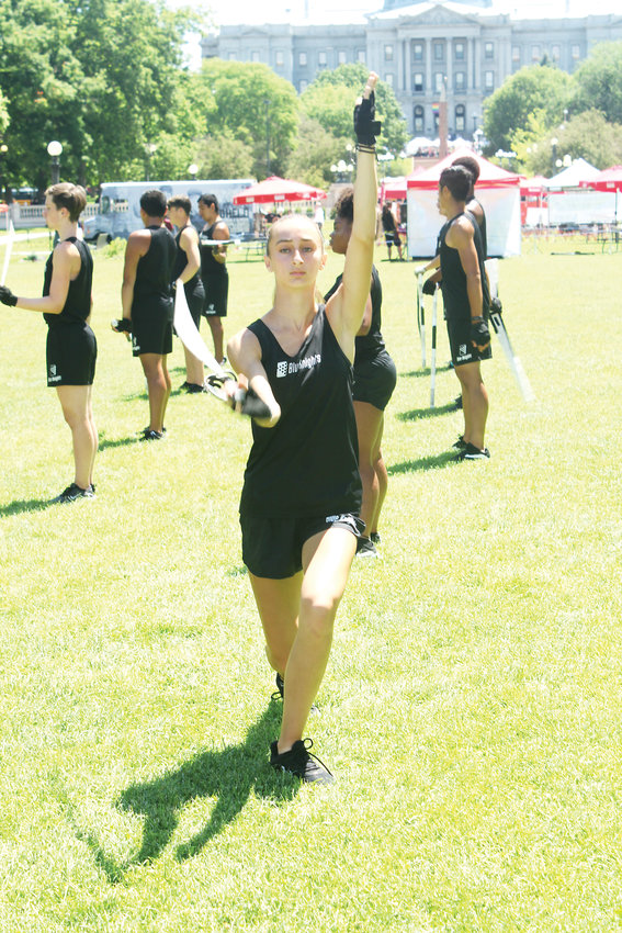 Claire Wells stretches before a Blue Knights performance in Denver. The drum corps performed during the Civic Center Eats event.