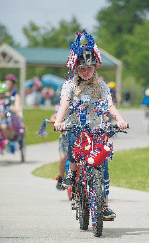 Jacklyn Dettling, 10, of Milliken, rides the pedestrian/cyclist trail, which circles Webster Lake, at E. B. Rains Jr. Memorial Park, during the Pedals and Paws event of the city's annual 4th of July celebration. Dettling is the granddaughter of Kathy and George Shellbaker of Northglenn, who've seen many of their children and grandchildren, participate in the event.