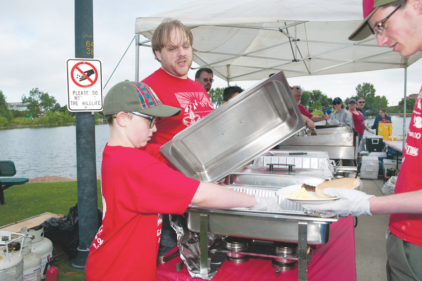 Riley Gursk, 11, of Northglenn, left, and Aaron Tucker, both from Boy Scout Troop 98, help serve scambled eggs and saugage, during the Troop’s annual 4th of July Pancake Breakfast, at E.B. Rains, Jr. Memorial Park.