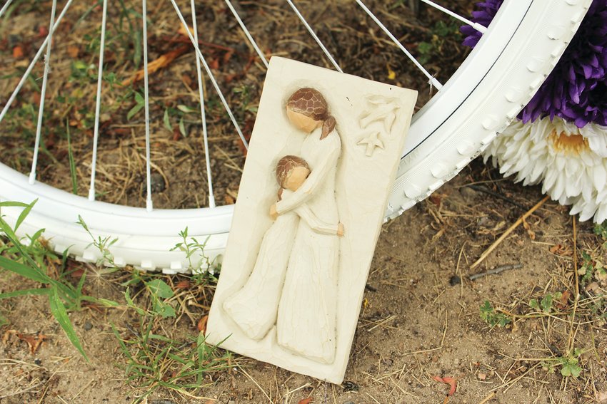 A plaque of a mother and child leans against Alexis Bounds’ ghost bike in Denver. Bounds was the mother of two young boys.