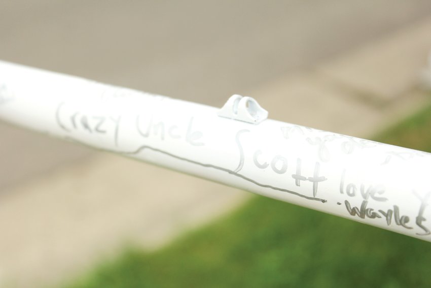 Friends and relatives of Scott Hendrickson signed his ghost bike with love for “crazy Uncle Scott.” Hendrickson was hit nearby to West-Bar-Val-Wood Park in Denver. A resident of the neighborhood said cars frequently speed in the area.