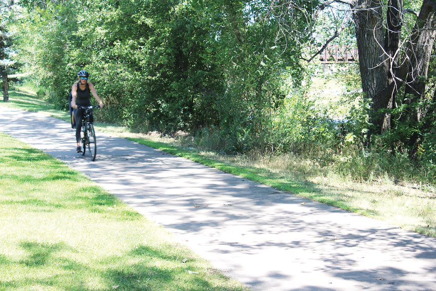 A woman rides her bike recently on the South Platte River Trail in Englewood.
