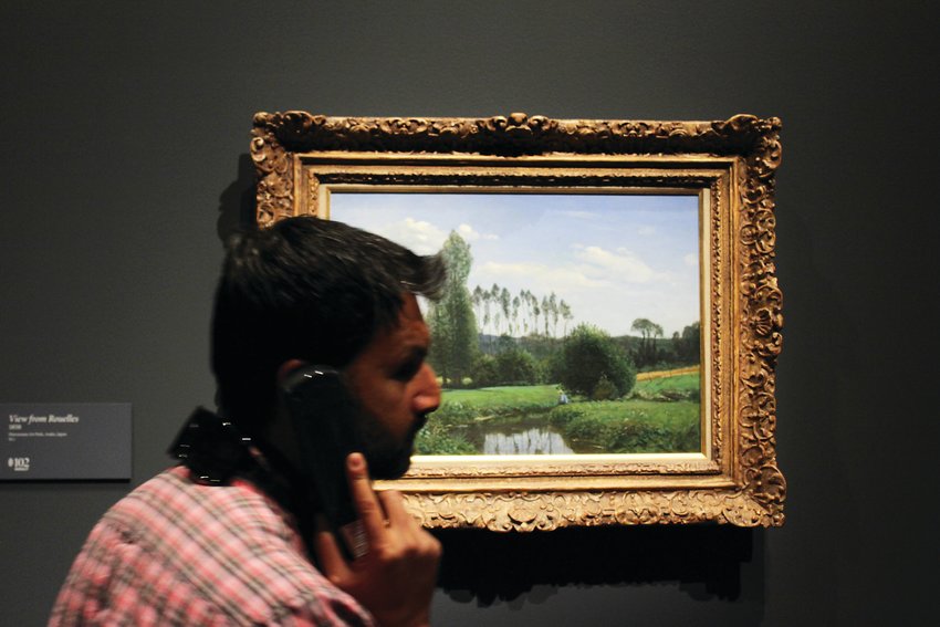 A man listens to the audio tour, stopping at the first known painting by Monet. The Monet exhibit features works from the artist’s entire career.