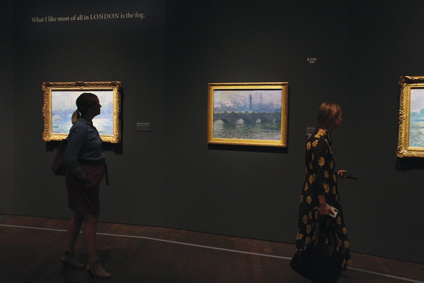 People walk by a series of Monet bridge paintings at the Denver Art Museum. Monet often painted the same subject at different times of day or in different lighting conditions in order to capture its essence.