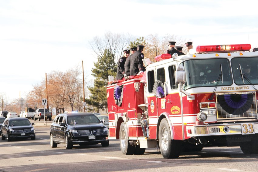 Fire rescue personnel ride atop a truck on East Hampden Avenue near South Colorado Boulevard in the procession of emergency vehicles after the memorial service for Troy Jackson Dec. 20.