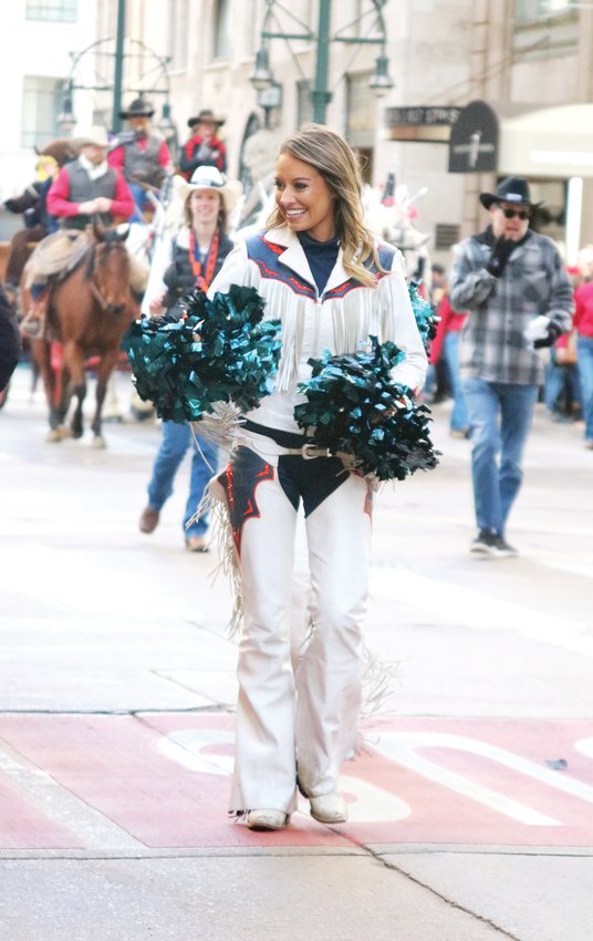 A Denver Broncos cheerleader smiles and waves her pompoms at the crowd during the Stock Show Kick-off Parade in downtown Denver on Jan. 9.