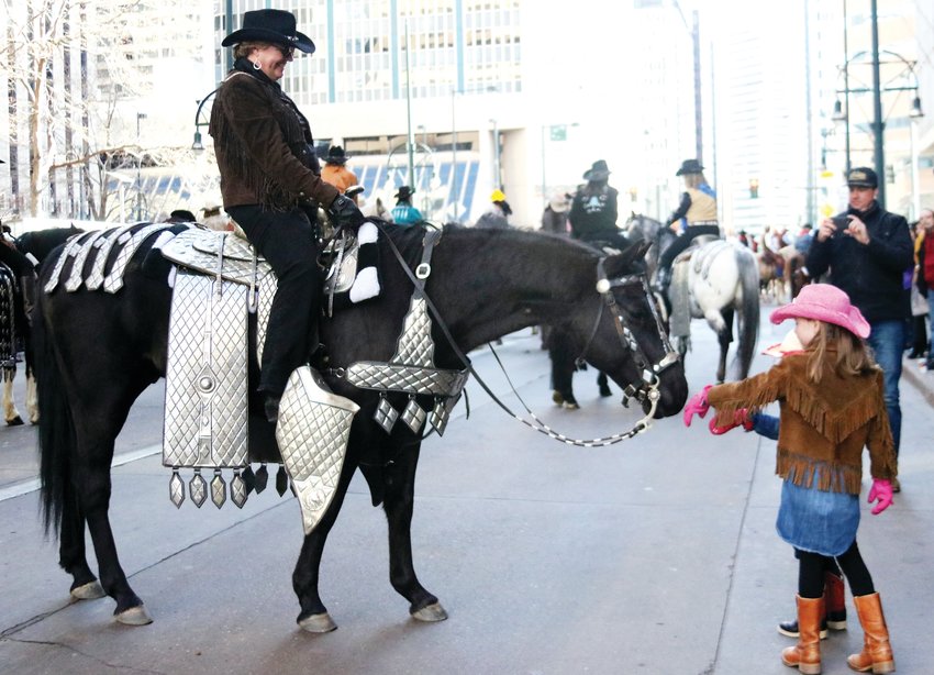 Essie Ohlson, 7, and her sister Belle, 3, of Boulder interact with a horse and rider during the Stock Show Kick-off Parade in downtown Denver on Jan. 9.