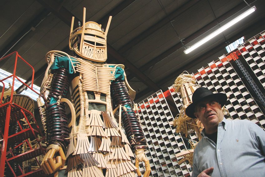 Steve Farland, owner of the Chairman, stands beside "The Guardian," one of seven towering statues made of chairs.