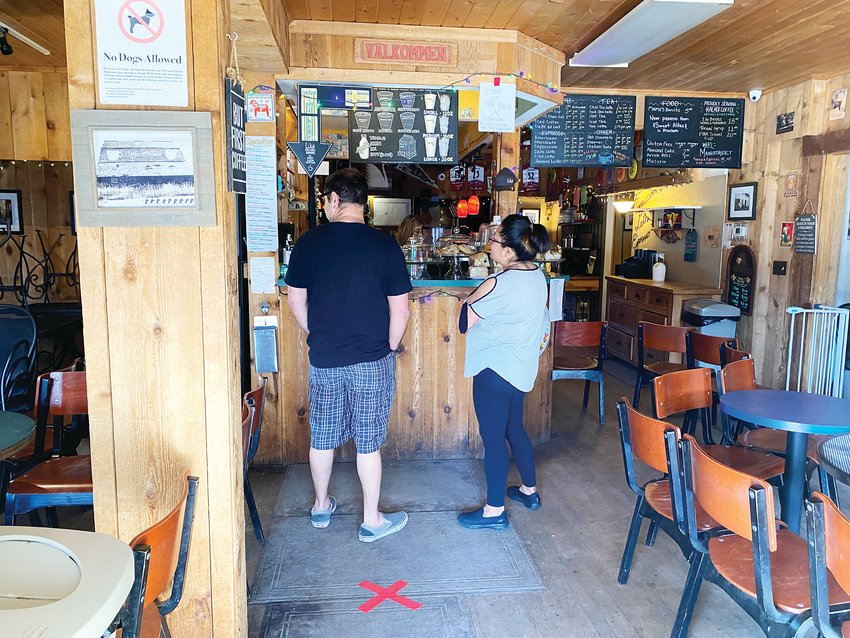 A couple wait for their coffee at Fika Coffee House in downtown Parker March 22. The shop is open only for to-go orders with the seating area closed. Customers must stand at the red 'X' on the ground to keep a safe distance six feet from employees.