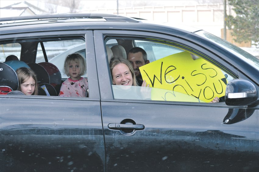 The Beach Family, Nyssa and Ryan in the front seat and Hannah, 6, and Maddie 4, wait in their warm car outside of Advent Lutheran Church in Westminster for a glimpse of Pastor Barb Martens Easter Sunday. An handful of the church's congregation pulled into the church's parking lot honk horns, flash their lights and wave signs to greet the pastor.