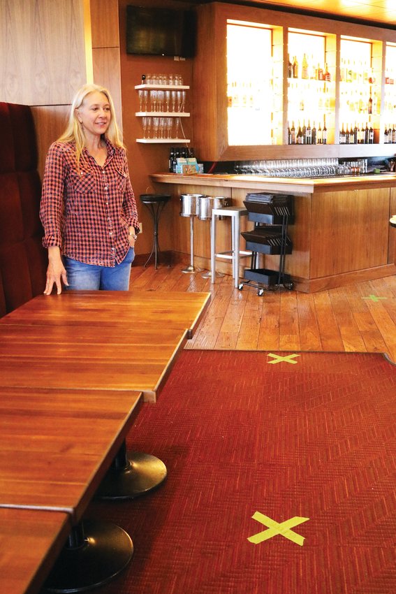 Co-owner Delinda Fatianow stands inside one of the Indulge Bistro and Wine Bar Highlands Ranch locations April 1. The x's on the floor, which are 6 feet apart, indicate where the store's customers can stand as they pick up grocery items.