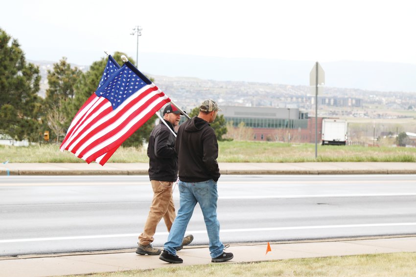 Jed Gilman, left, and John Hulse drove over an hour to Castle Rock May 11 to carry American flags in front of C &amp; C restaurant in support of the business.