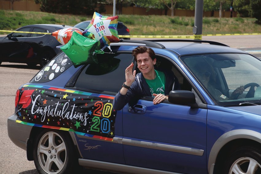 A ThunderRidge High School senior with a decorated car waves to his teachers as he drives in a May 15 parade.