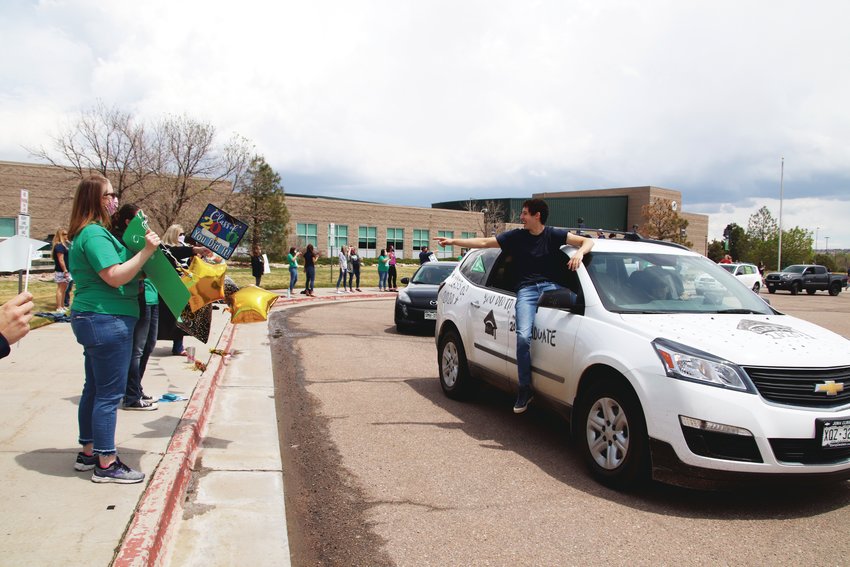 One ThunderRidge High School graduate sits with a leg outside the window while he points at a teacher during a May 15 parade.