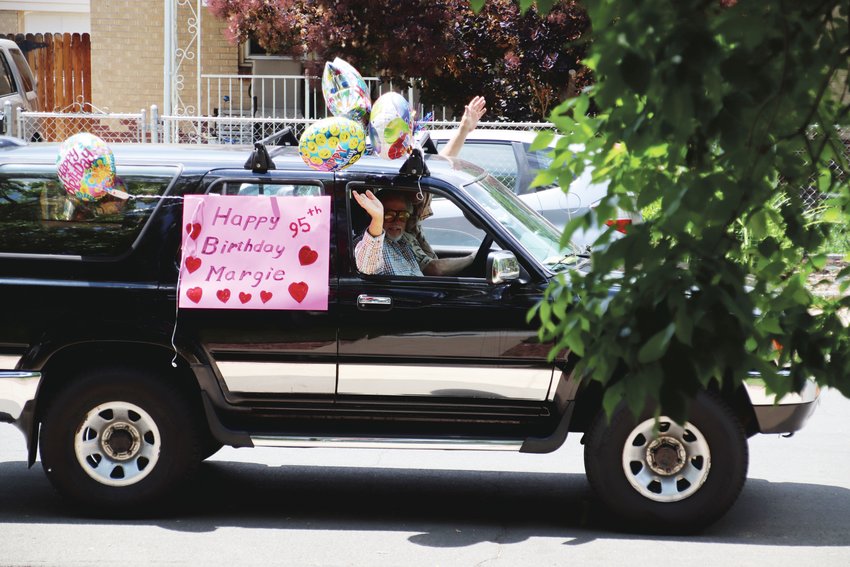 Neighbors Thomas Gardner and Bill Dolzal drive by Margie Ingram's house in a car decked out for Ingram's 95th birthday.