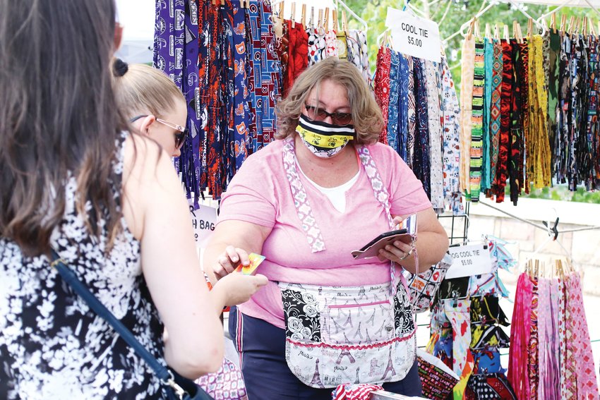 Pat Schuessler rings up a customer at her Everything Fab stand, where she sells crafted cool ties, trash bags and collapsible dog bowls.