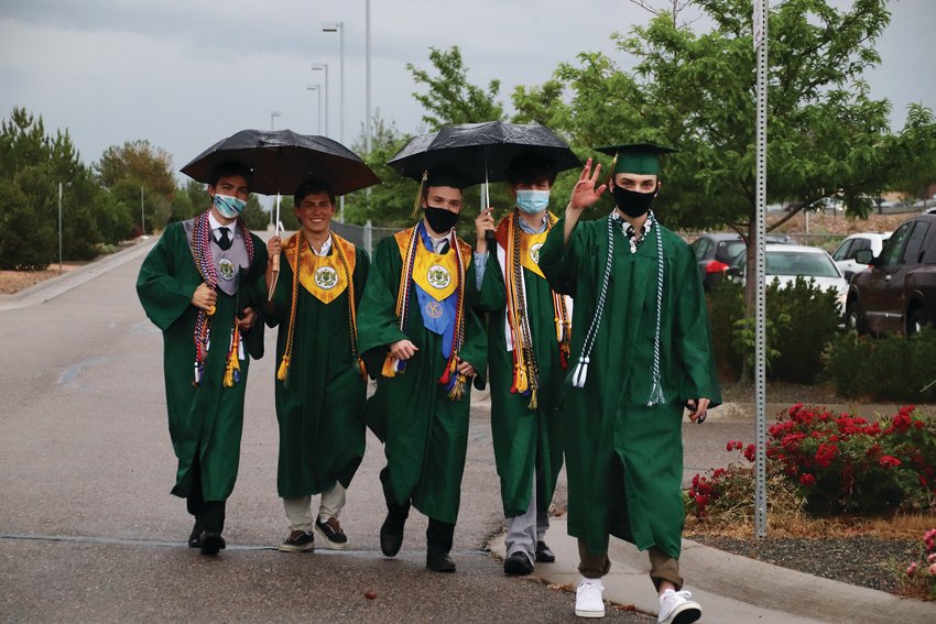 A group of Mountain Vista High School seniors walk through the parking lot at EchoPark Stadium in Parker after their graduation ceremony was delayed by lightning.