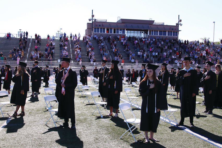 Castle View High School students stand for the national anthem during their graduation ceremony June 26. Students and their guests were all spaced 6 feet apart during the event.