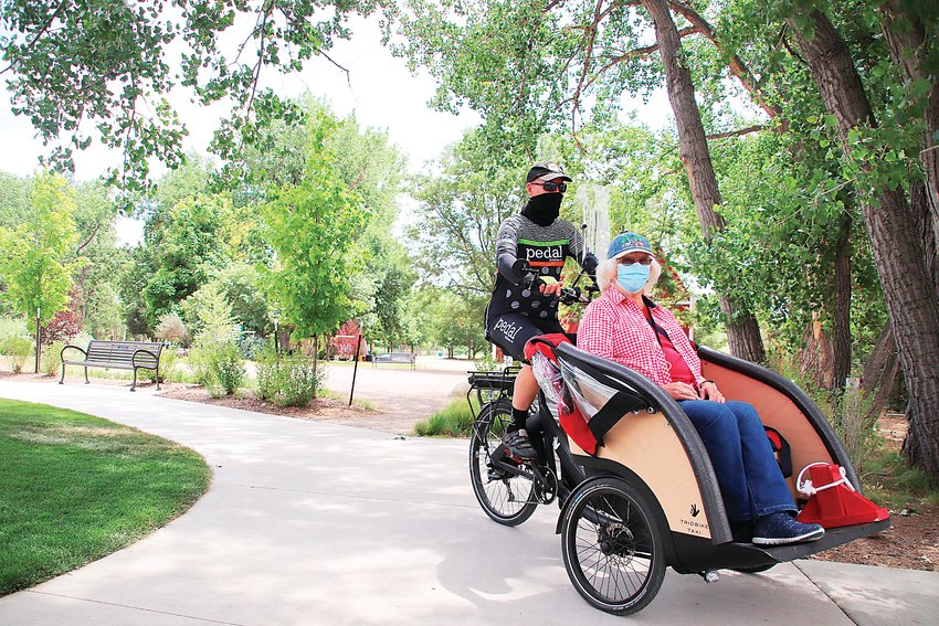 Former Littleton Mayor Phil Cernanec, left, gives Bonnie Douglas a “trishaw” ride through Hudson Gardens on July 28. Cernanec helped found Littleton’s chapter of Cycling Without Age, which takes seniors on rides around town.