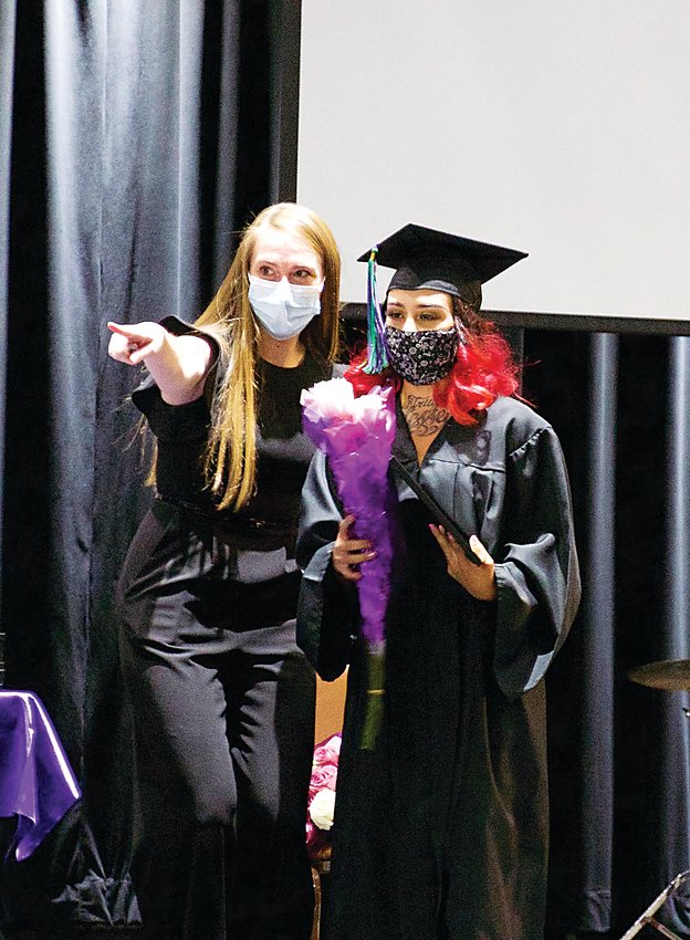A Hope House grad takes a photo on stage after receiving her diploma.