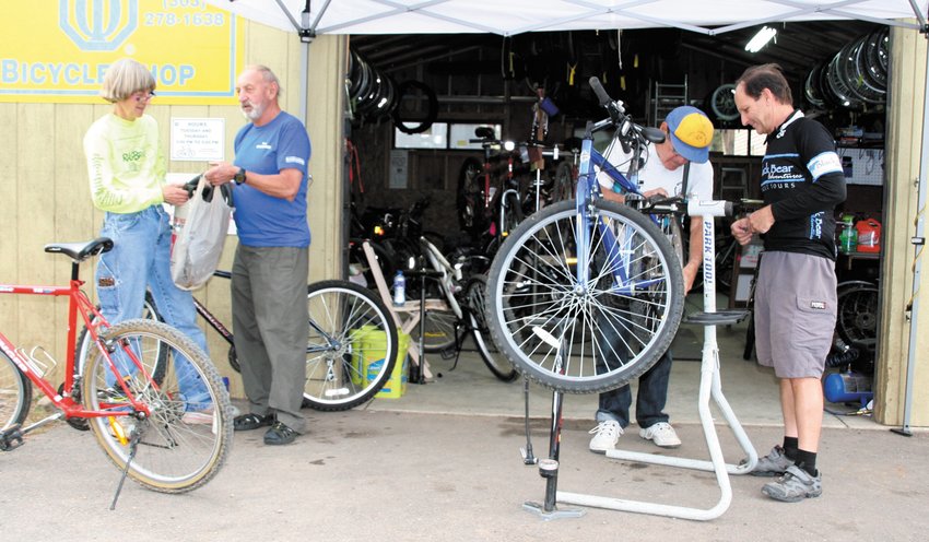 A 2015 photo of Golden Optimists volunteers at work. From left, Suzy Stutzman chats with Janusz Kokot while Howard Bagdad and Scott Perrin, far right, work on a bike’s tires at the Golden Optimists’ former shop location at Heritage Square.
