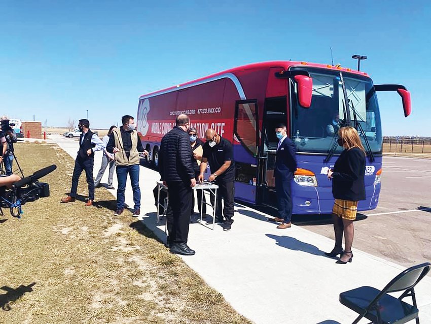 Gov. Jared Polis, center, visits a mobile vaccine clinic, an effort supported by state officials to bring vaccinations sites to locations around Colorado. The state has two bus routes and was to announce a third soon.