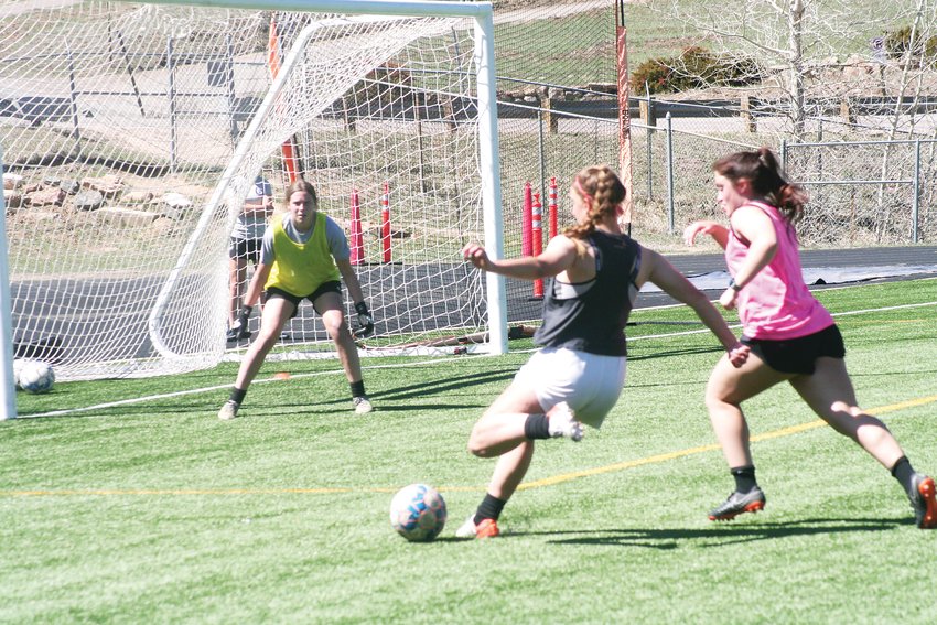 The Evergreen girls varsity squad practices a competitive one-on-one drill with goalkeeper Aubrey Huerta waiting in goal to stop the shot.
