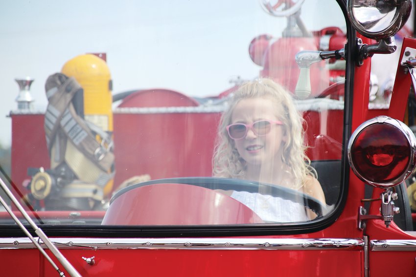 Isla White, 7, sits behind the wheel of a vintage fire rig.