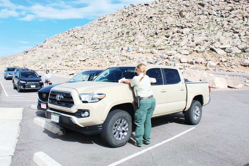 U.S. Forest Service Ranger Hillary Schuler conducts parking enforcement on July 22 at the summit parking lot on Mount Evans. This summer, the U.S. Forest Service and its partners are requiring reservations during peak hours at the major parking areas along the Mount Evans Scenic Byway.