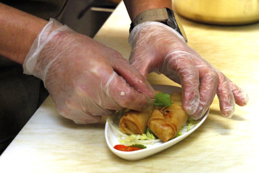 Kitchen assistant Josue Benavides garnishes a pair of spring rolls at Lone Tree’s Honey Pig Cafe on Sept. 6.