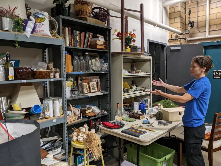 Megan Davis, a local theater artist, demonstrates the need for more prop storage at Firehouse Theater Company in Aurora. The Resource Sharing Initiative could potentially help participating theaters save money, time, storage space and stress by joining forces.