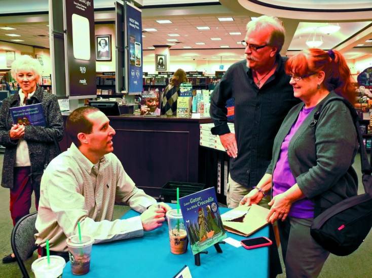 Mike Fortunato, left, discusses his book, Later Gator, In a While Crocodile with people during his book signing on Dec. 15 at Barnes & Noble in Westminster.