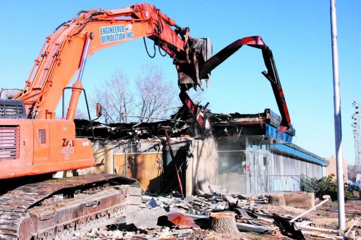 The excavator operator pulls to remove one of the steel support beams as demolition begins Dec. 23 on the main Englewood HIgh School buildings. Demolition will take four to five weeks and, once the area is cleared, work will begin on Phase Two construction of a seventh- through-12th-grade campus on the site.