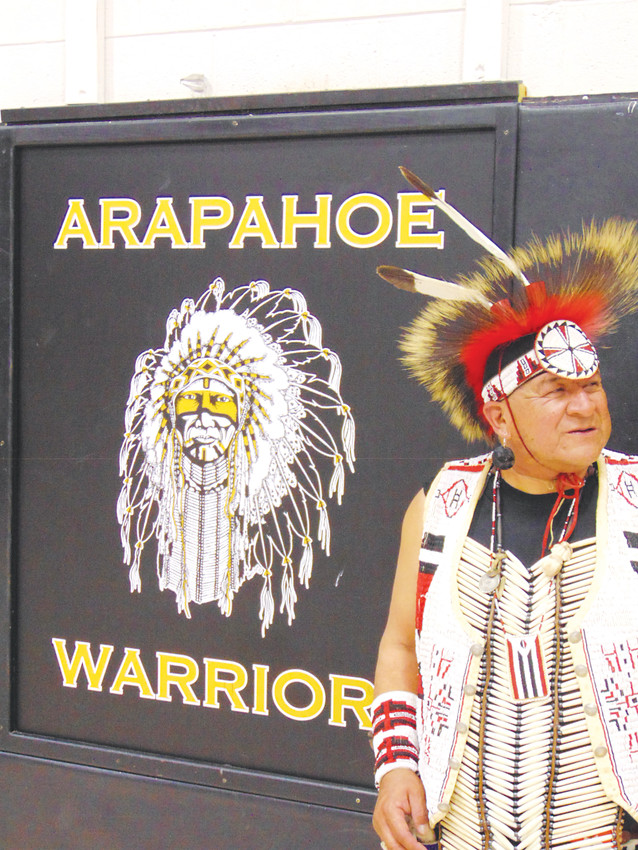 Lawrence Bell stands beside a painting of Arapahoe High School's Warrior mascot, which was painted by an Arapaho artist.