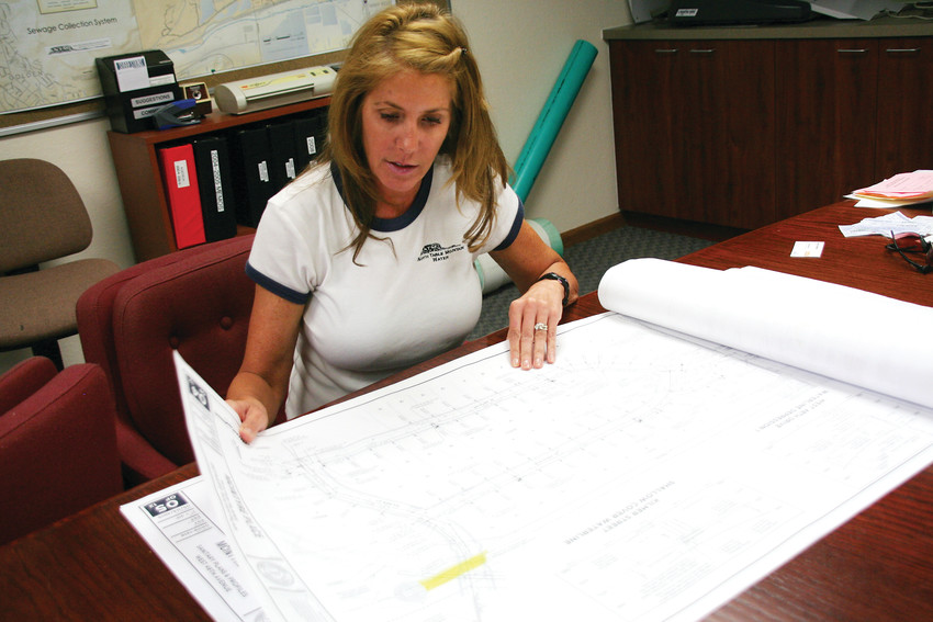Wendy Weiman, the project engineer for North Table Mountain Water and Sanitation District, looks through water and sewer construction plans for a project she’s working on at her office in Golden.