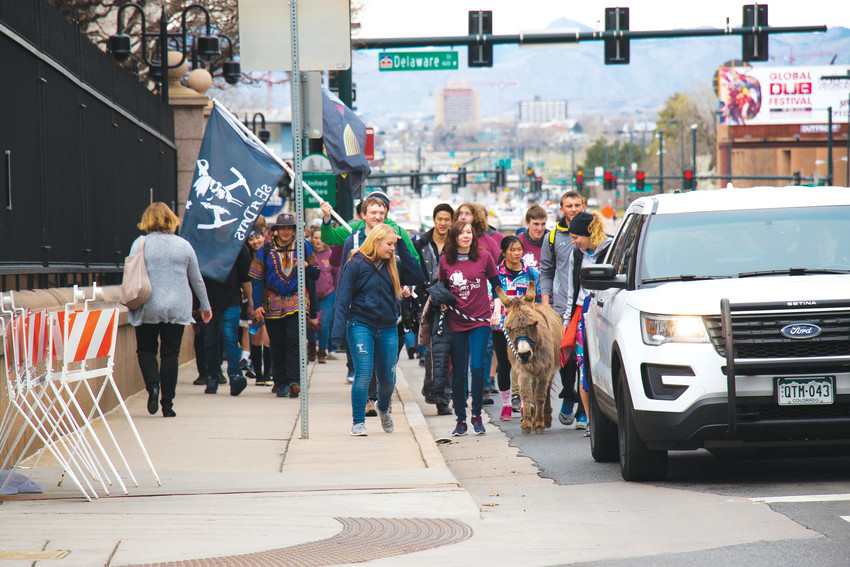 Colorado School of Mines students make their way east along Colfax Avenue on April 13, led by Blaster the school mascot, for the annual Ore Cart Pull walk to the capitol building. The march from Golden to Civic Center Park in Denver is a school tradition.