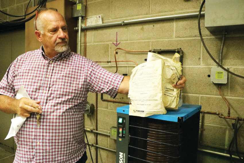 Wayne Blazek, facilities planning manager at Douglas County School District, holds an outdated manual in a boiler room at Ponderosa High School in Parker. A bond would help address the school's heating and cooling systems.