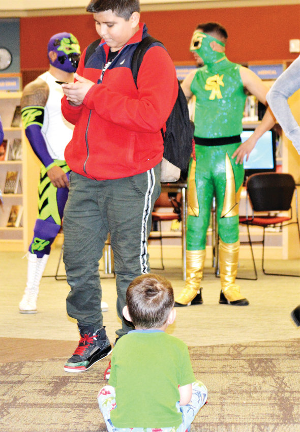 Four-year-old Jesus Martinez sits and refuses to move as library patrons go up to meet luchadores Heros and Sol Azteca Feb. 26 at the Anythink Library York Street branch.