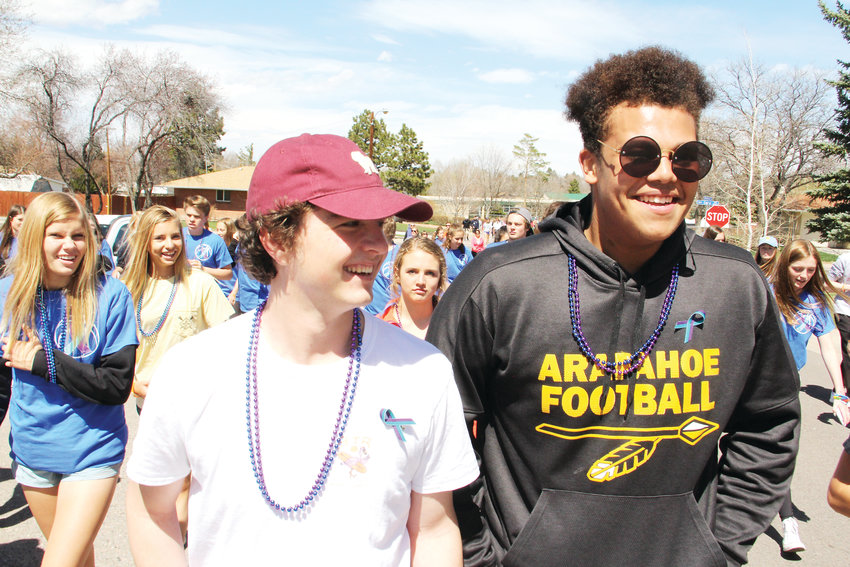 Tyler Adams, left, and Jason Washington, seniors on the Arapahoe High School football team, talk to friends during the suicide-prevention walk April 14 in the neighborhood near Arapahoe High. “All the guys from football that I know are here,” Adams said.